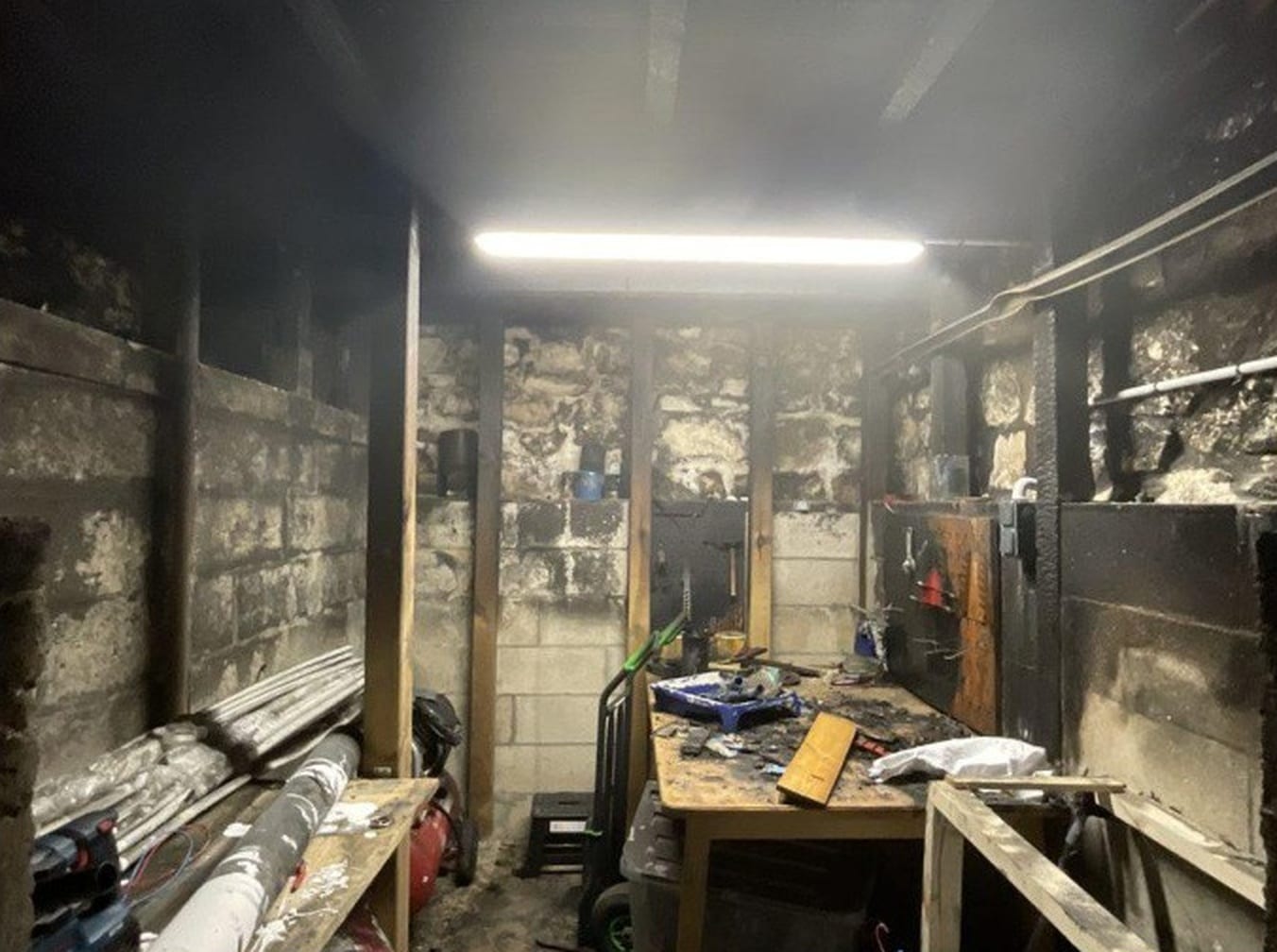 Sous-sol d'une maison après incendie, structure bois noircie
